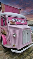 The Waffles & Heaven food truck parked at a sunny festival, decorated with cloud and star motifs, serving happy customers.