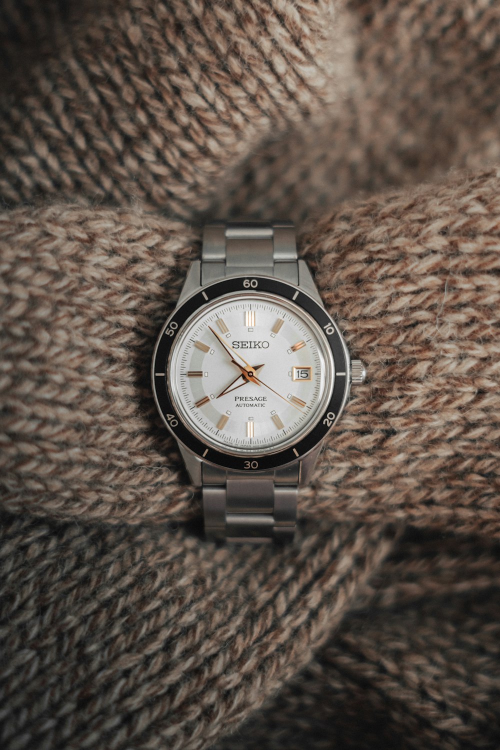 a silver watch on a brown surface