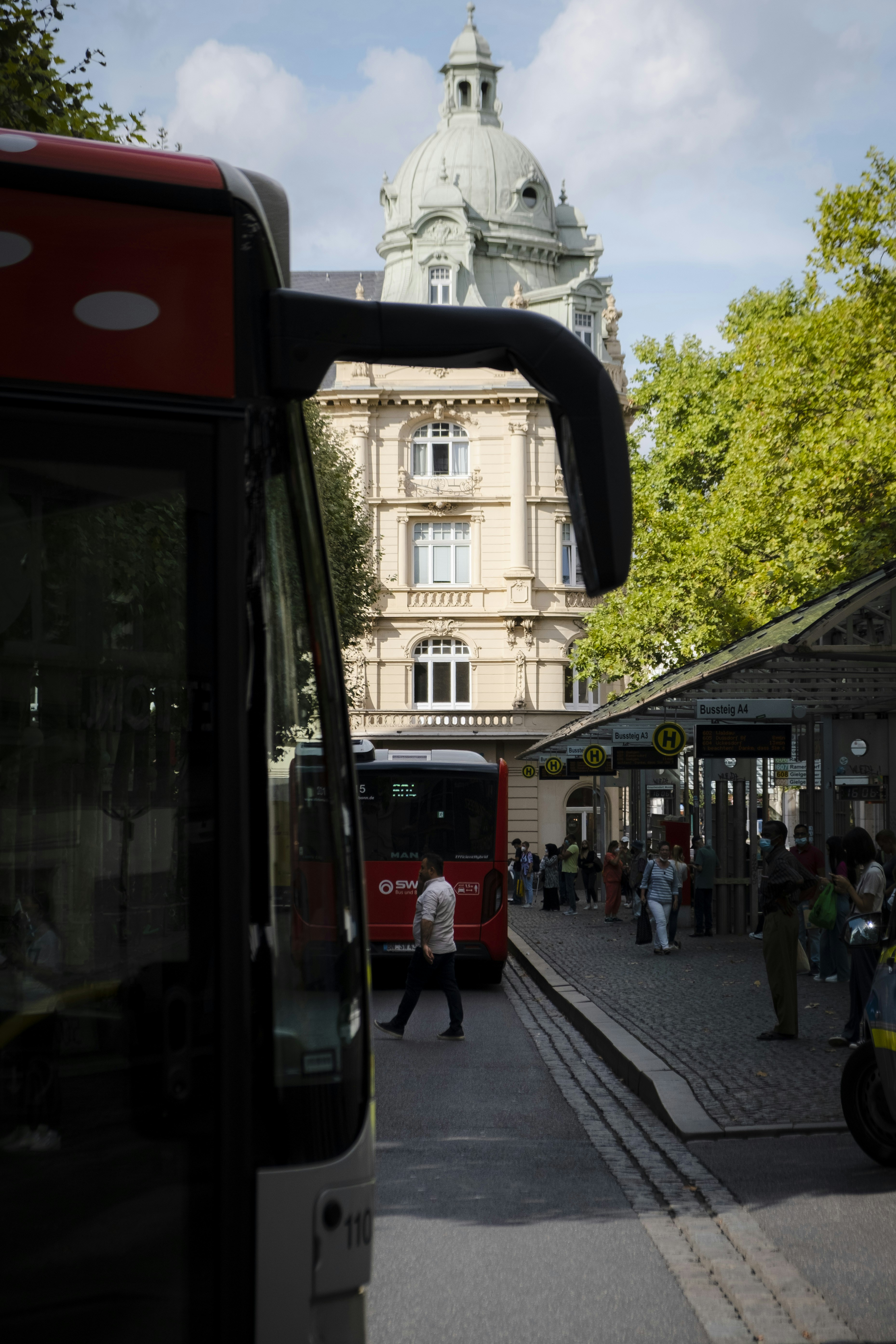 a group of people walk down a sidewalk next to a large building