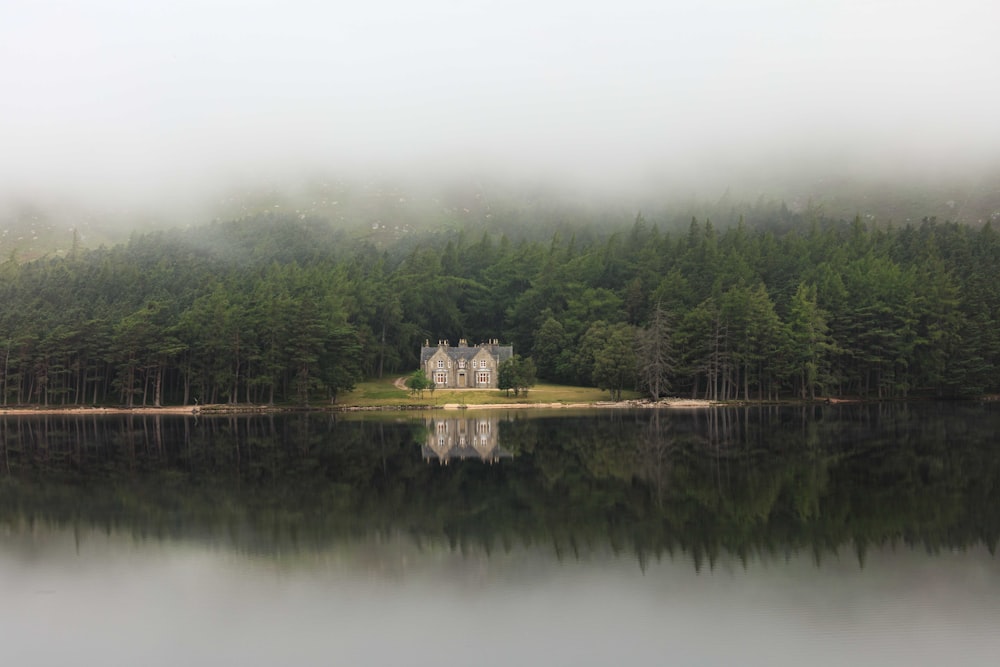 a building on a hill by a lake with trees