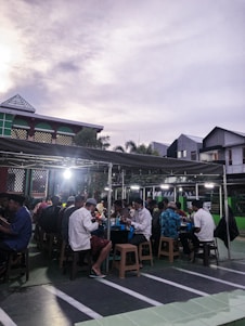 A group of diverse community members sharing a meal in a safe, welcoming outdoor setting.