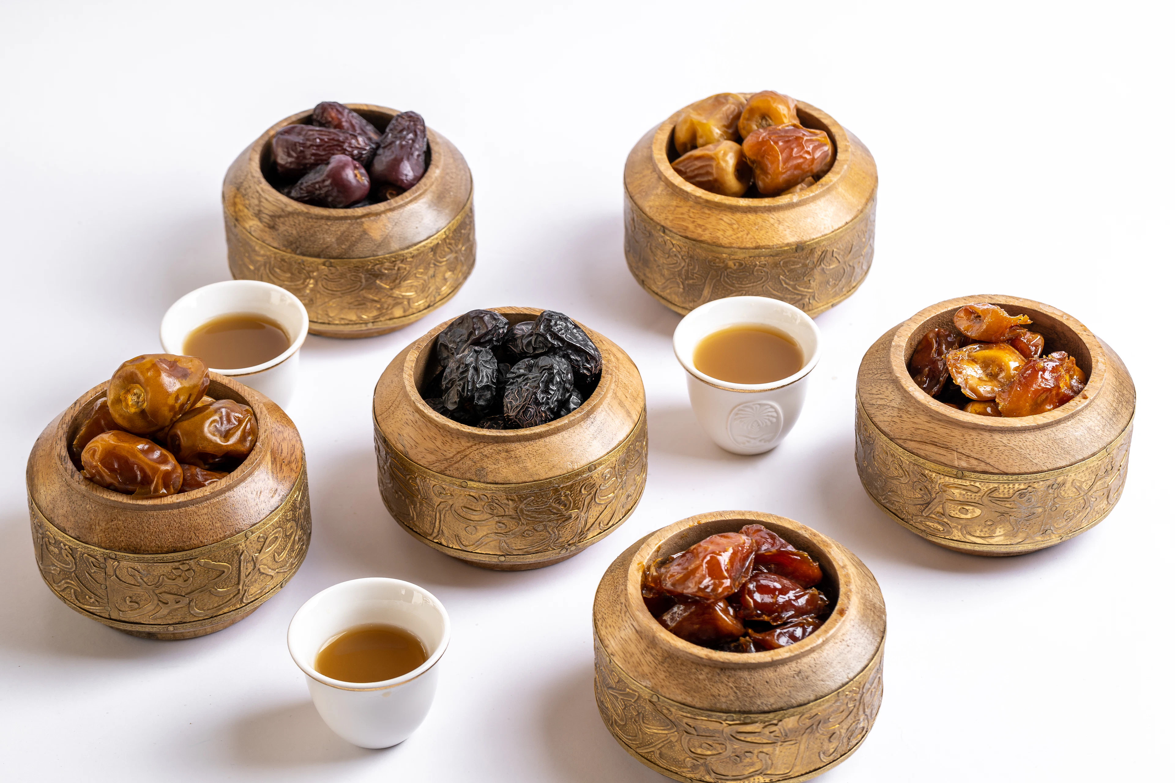 Kurma dalam mangkuk keemasan dengan cangkir kopi Arab