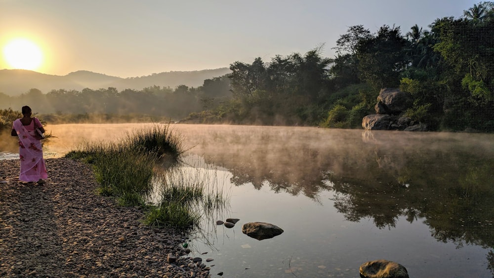 a person standing next to a pond