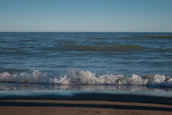 Gentle waves lapping a pristine shoreline under a deep blue sky, evoking calm and purity.