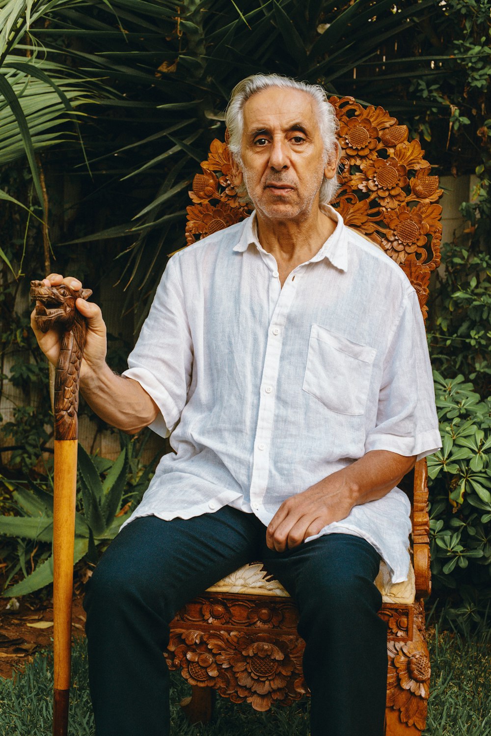 a man sitting on a chair holding a stick