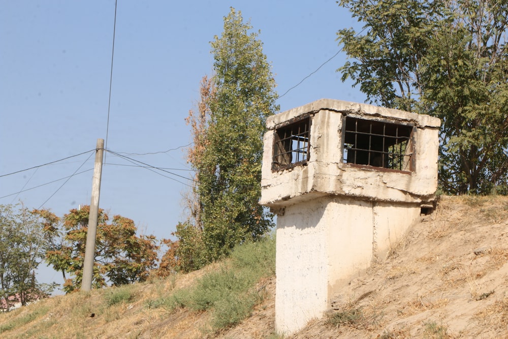 a white building with windows on a hill with trees and blue sky