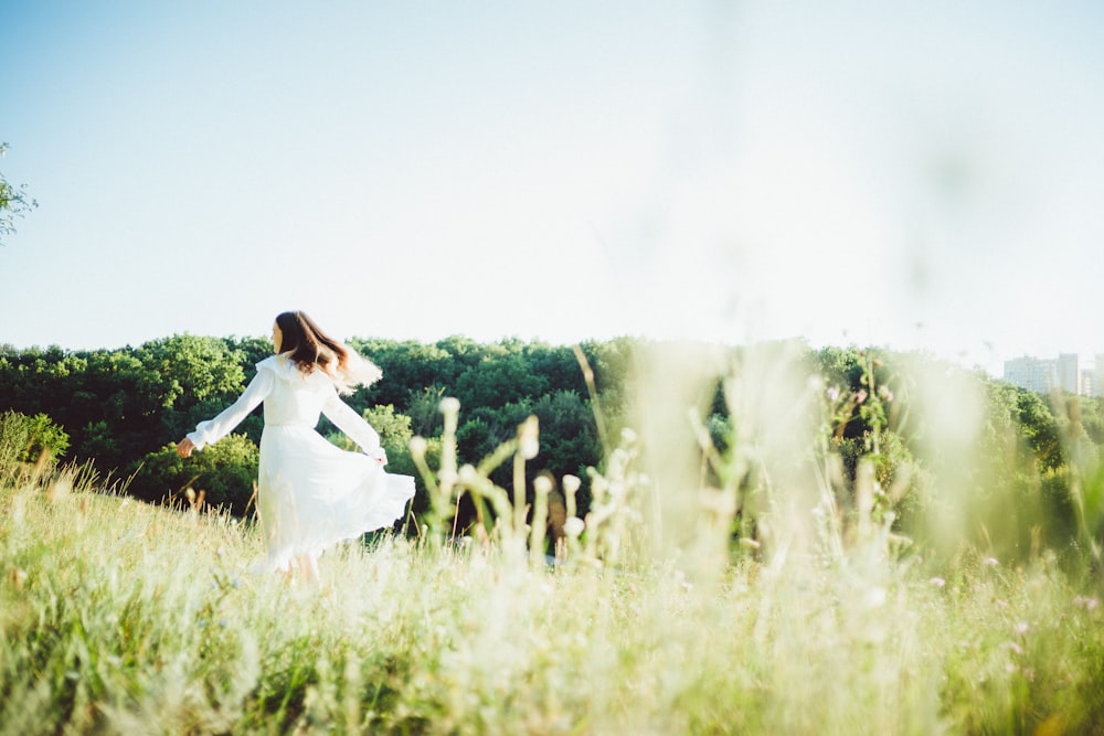 a person in a white dress walking through a field of tall grass