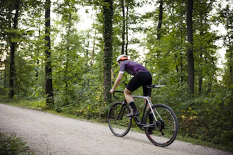 Cyclist wearing a vibrant jersey riding through a forest path with dappled sunlight