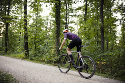 Cyclist wearing a vibrant jersey riding through a forest path with dappled sunlight