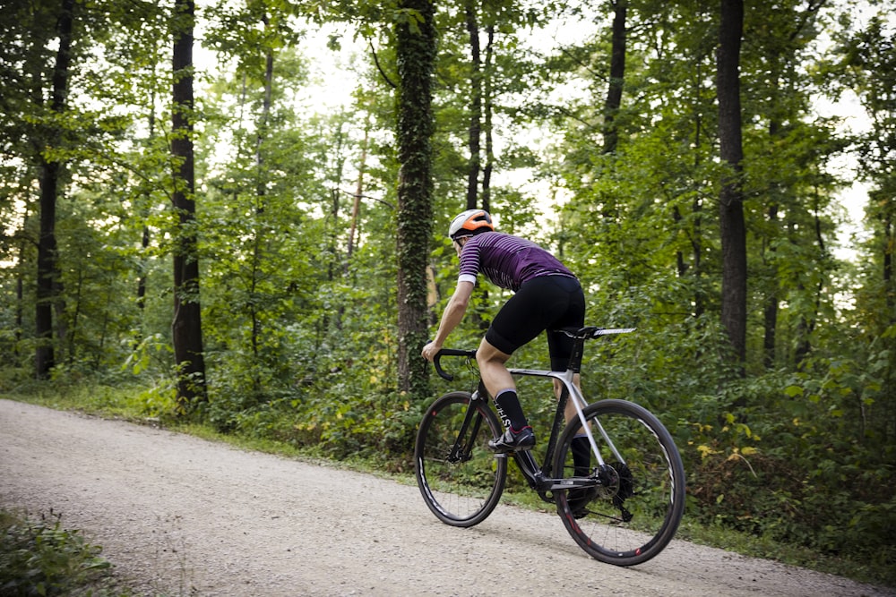 um homem andando de bicicleta em uma trilha na floresta
