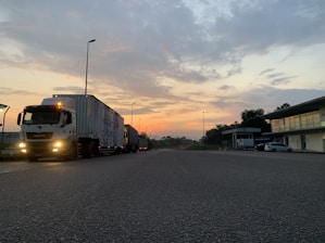 A sleek semi truck parked at a loading dock during sunset