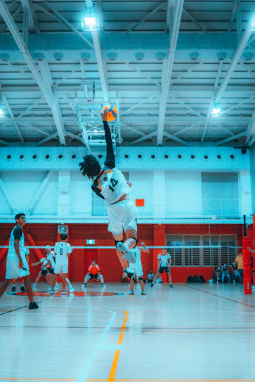 A dynamic action shot of a young volleyball player spiking the ball during a lively match.