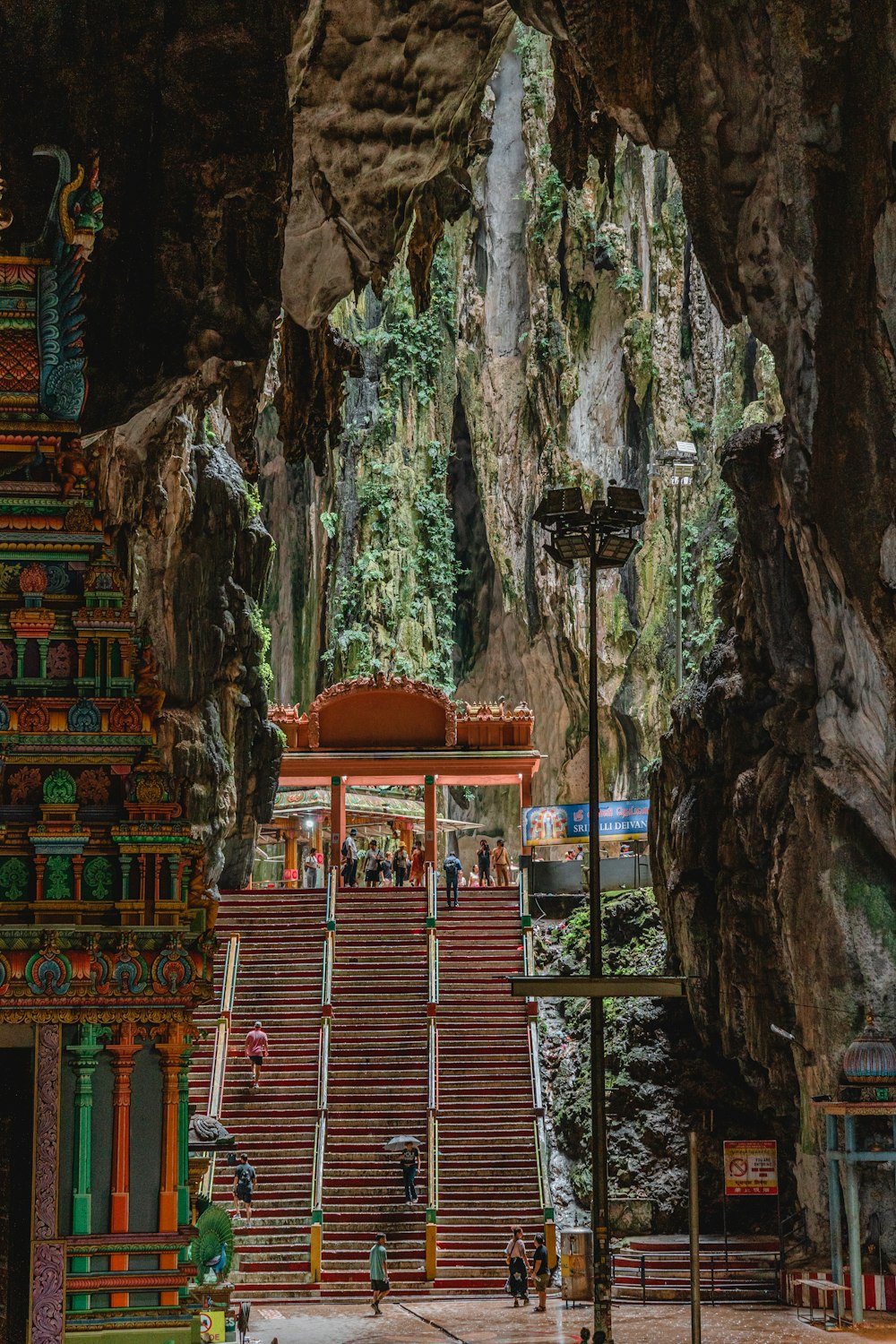 a large stone building with a large archway with Batu Caves in the background
