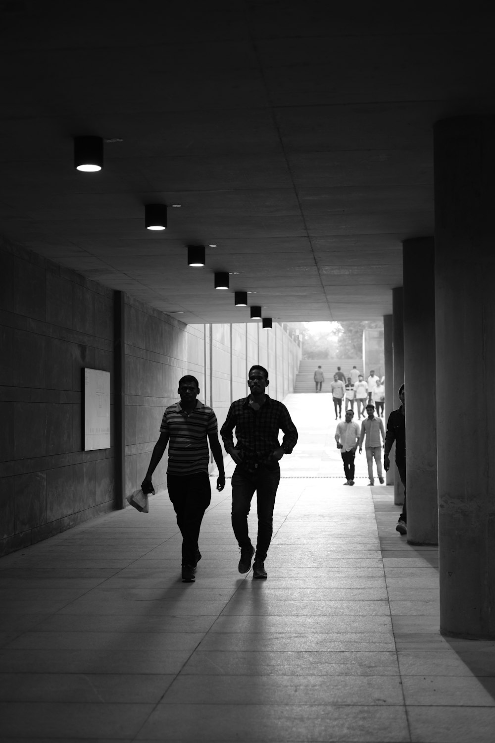 Un uomo e una donna che camminano lungo un corridoio con persone che camminano