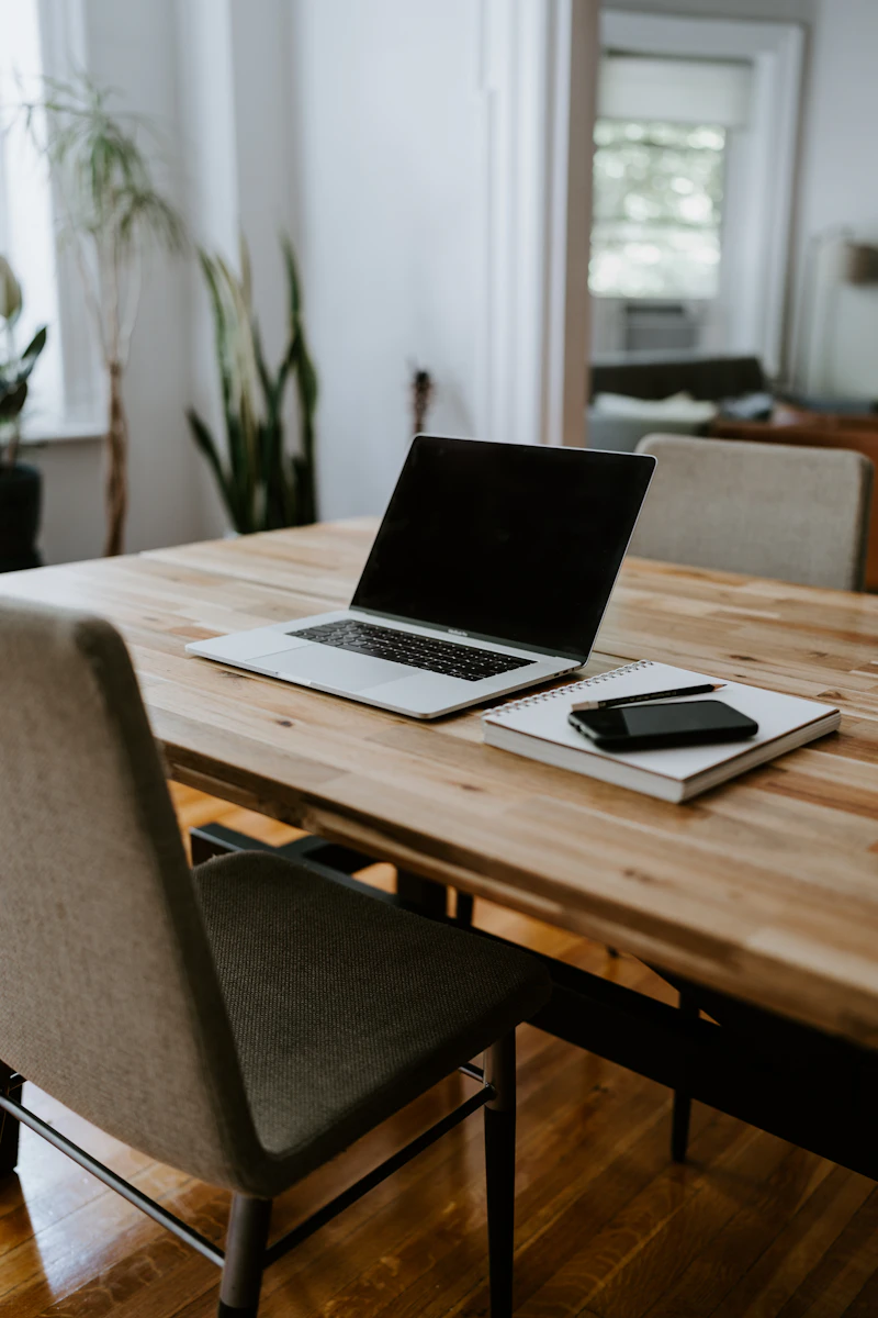 An empty wooden desk with an open laptop and notebook, ready for the day