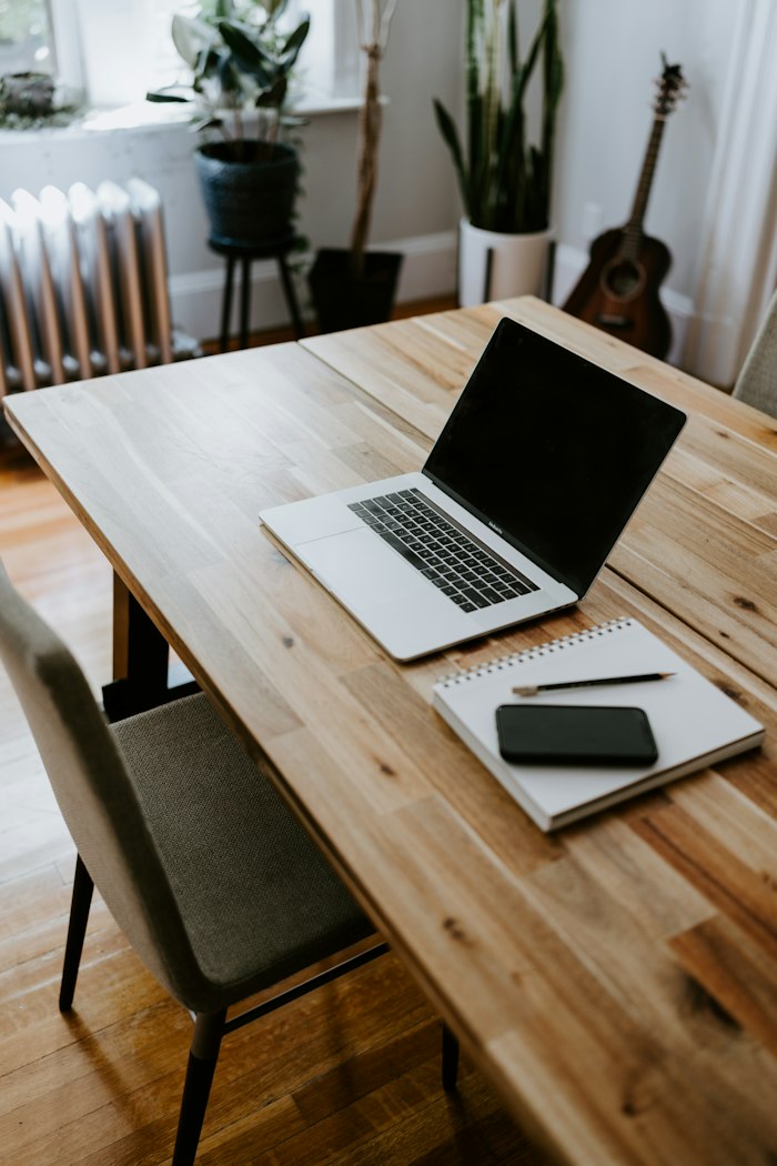 Laptop and notebook on a wooden table in a bright room