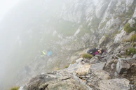 Close-up of hands gripping a tactical hiking stick while hiking up a rocky slope.