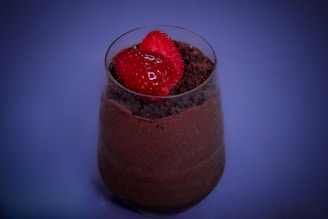 Close-up of a beautifully plated chocolate mousse dessert garnished with fresh raspberries and a delicate heart-shaped chocolate piece.