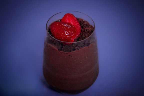 Close-up of a beautifully plated chocolate mousse dessert garnished with fresh raspberries and a delicate heart-shaped chocolate piece.