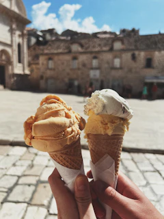 Smiling grandparents and grandchildren sharing ice cream cones in a sunny park.