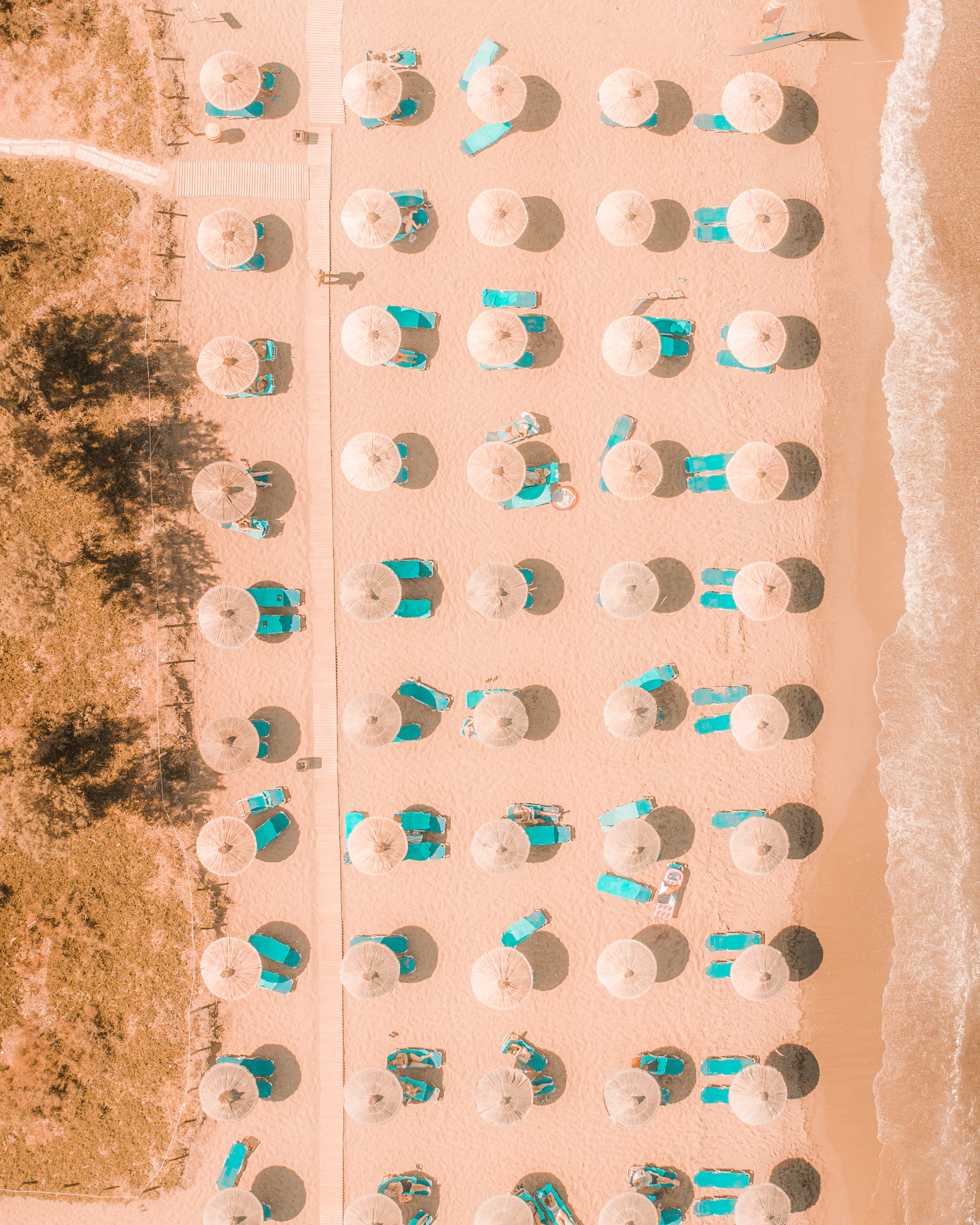 Kretischer Sandstrand mit Sonnenschirmen und türkisfarbenen Liegen