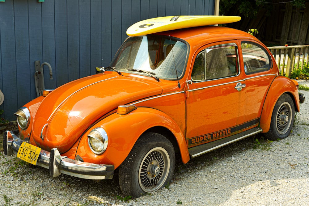 an orange car with a surfboard on top of it