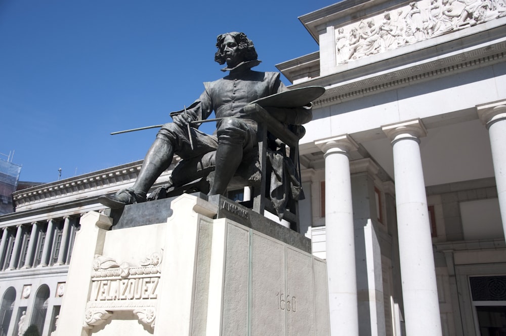 a statue of a man holding a gun in front of a building