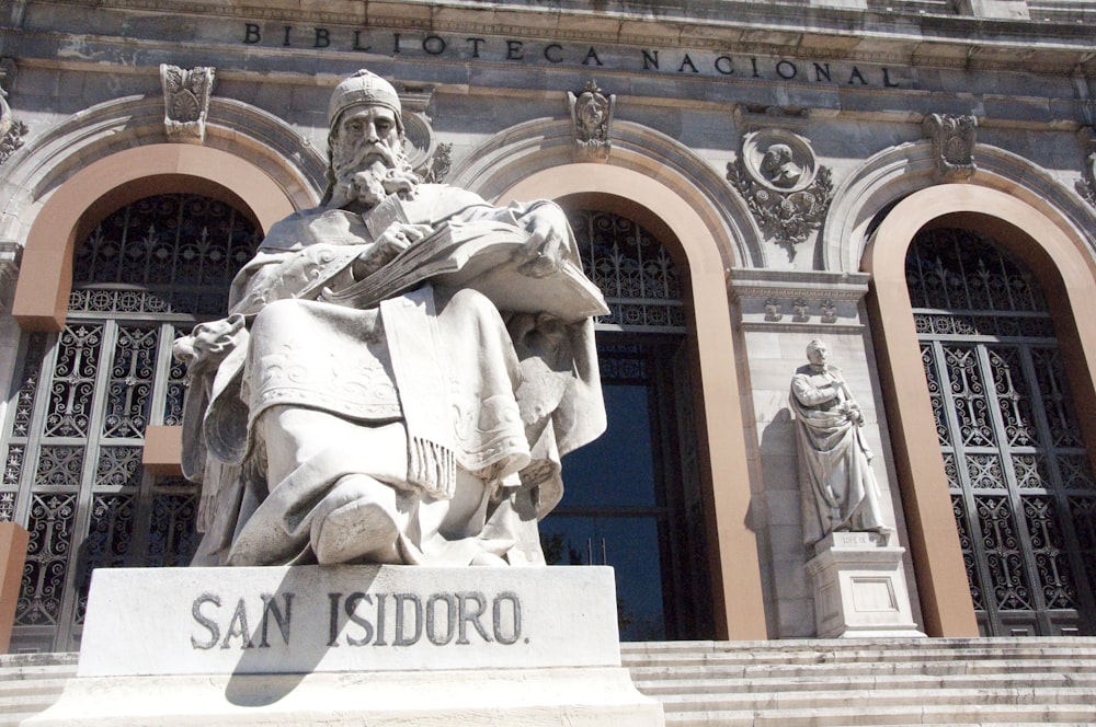 a statue of a person holding a staff in front of a building