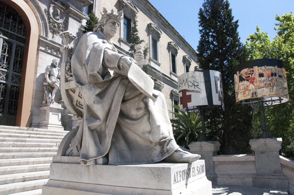 a statue of a person sitting on stairs outside of a building