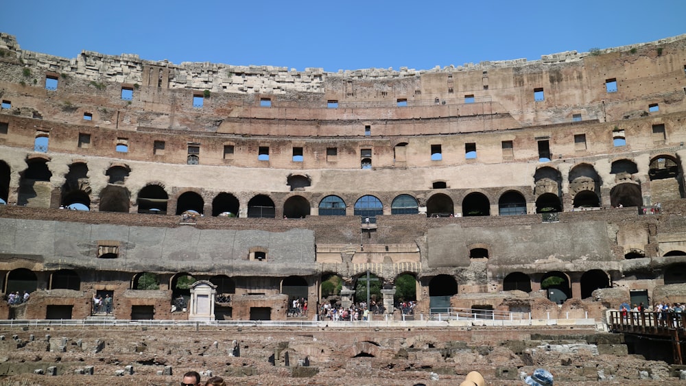 a large stone building with many arches with Colosseum in the background