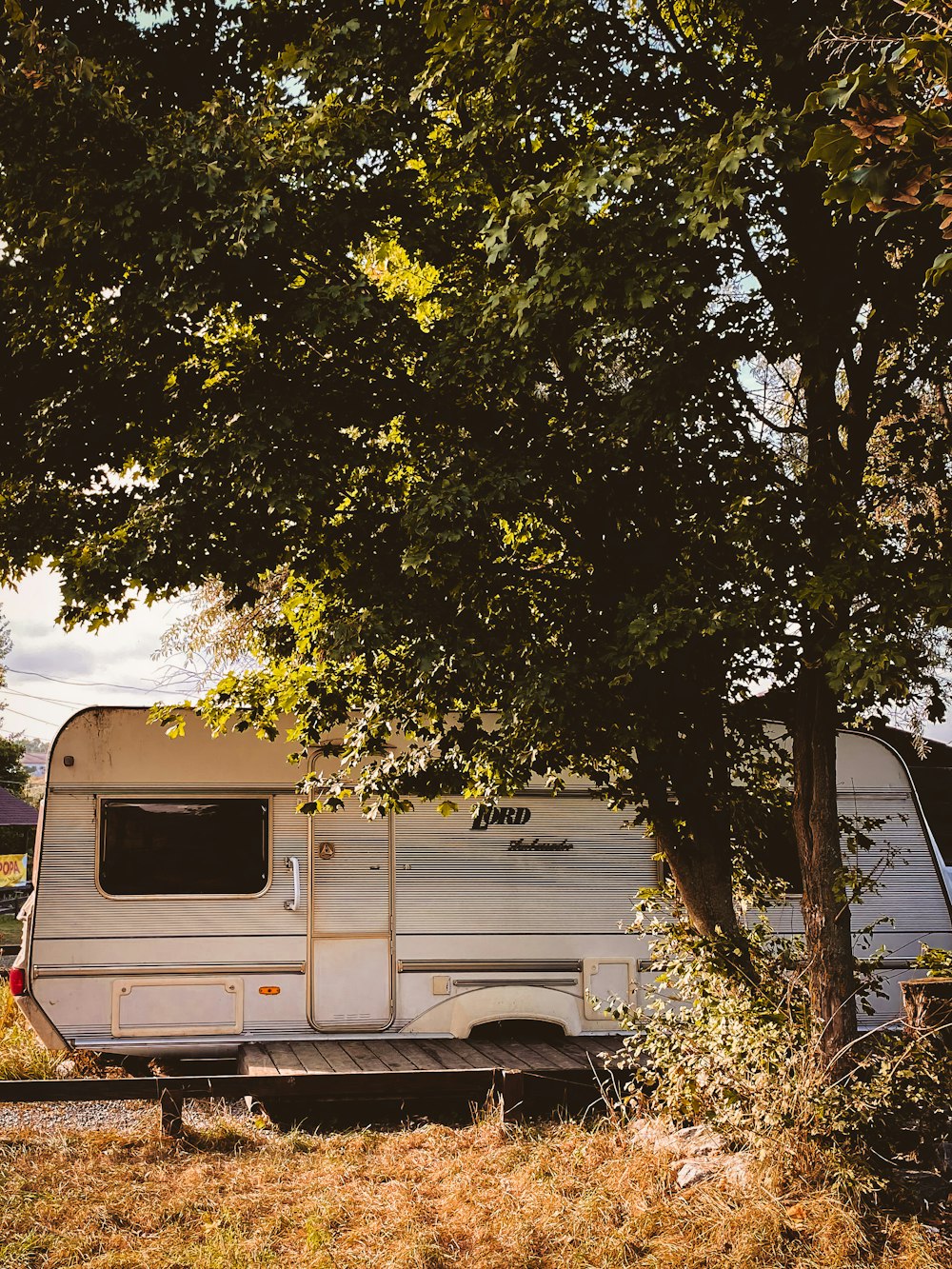 a trailer parked under a tree