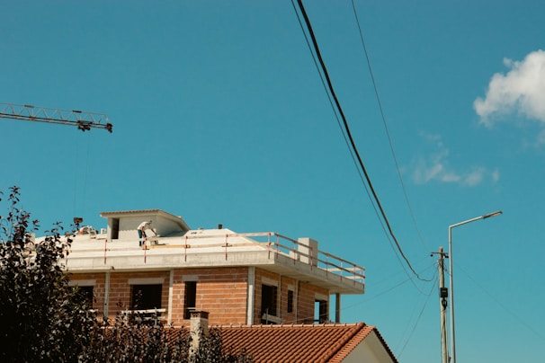 A skilled construction worker carefully inspecting a modern residential building site under clear skies.