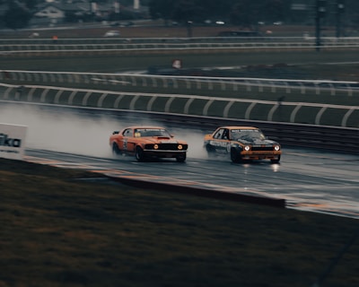 Dramatic wide shot of F1 cars racing closely on a wet circuit at sunset with dark clouds overhead.
