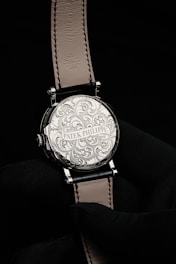 a silver watch on a black surface