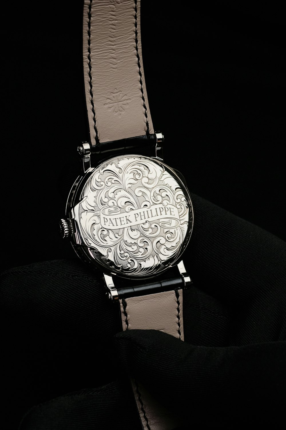 a silver watch on a black surface