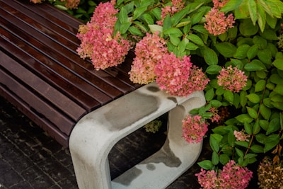 Close-up of a hand-stitched garden chair pad resting on a rustic wooden bench surrounded by blooming flowers.