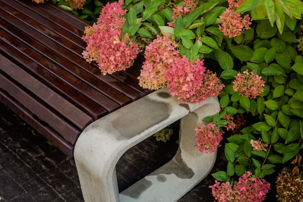 Close-up of a handcrafted wooden garden bench surrounded by blooming flowers and soft green grass.