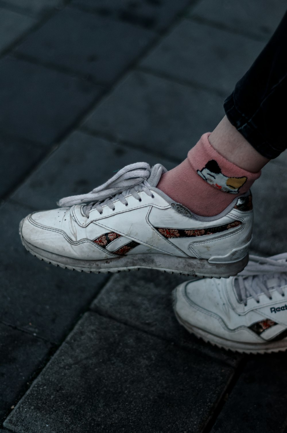 a person's feet wearing white shoes