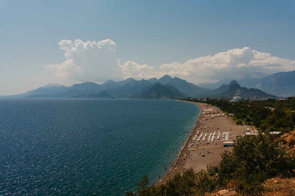 a beach with a body of water by it and mountains in the background