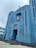 A large, blue-painted church with tall vertical windows and art deco architectural elements. The structure features a cross on top and a religious statue set into a niche above the main entrance. The building has a symmetrical facade with geometric designs.