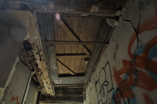 Photo of a rundown loft with peeling paint, cracked walls, and old wooden floors.