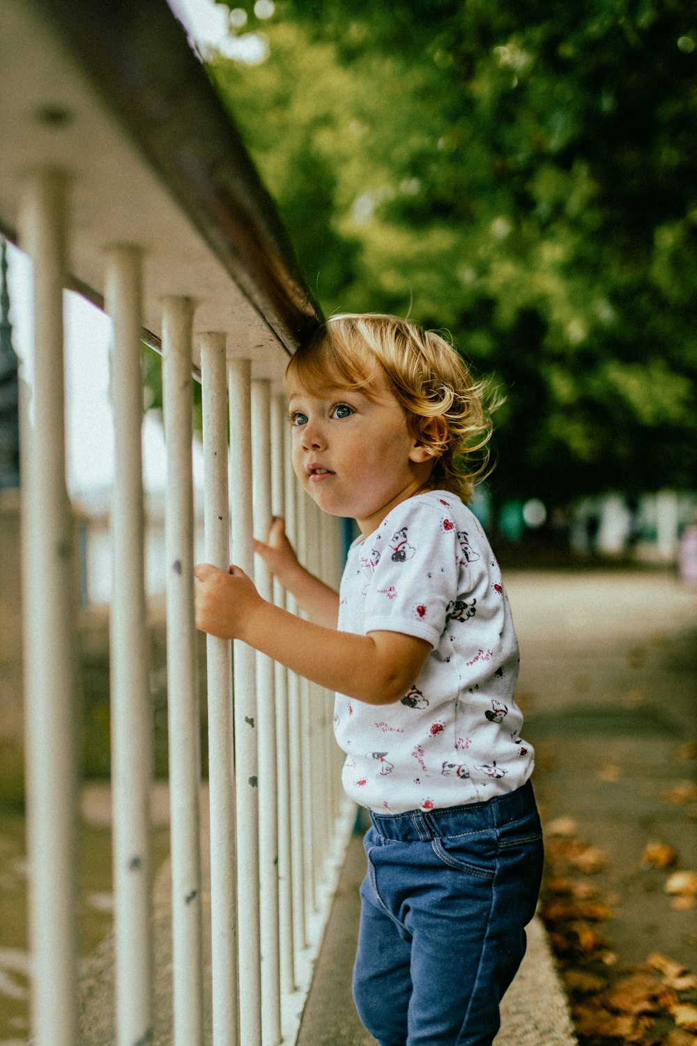 a young girl leaning against a fence