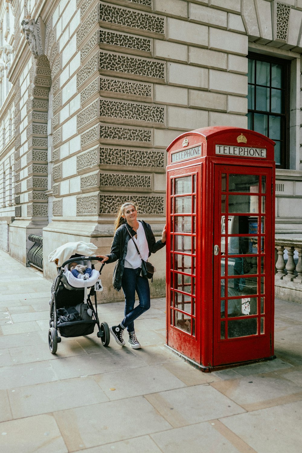 a person walking next to a red telephone booth