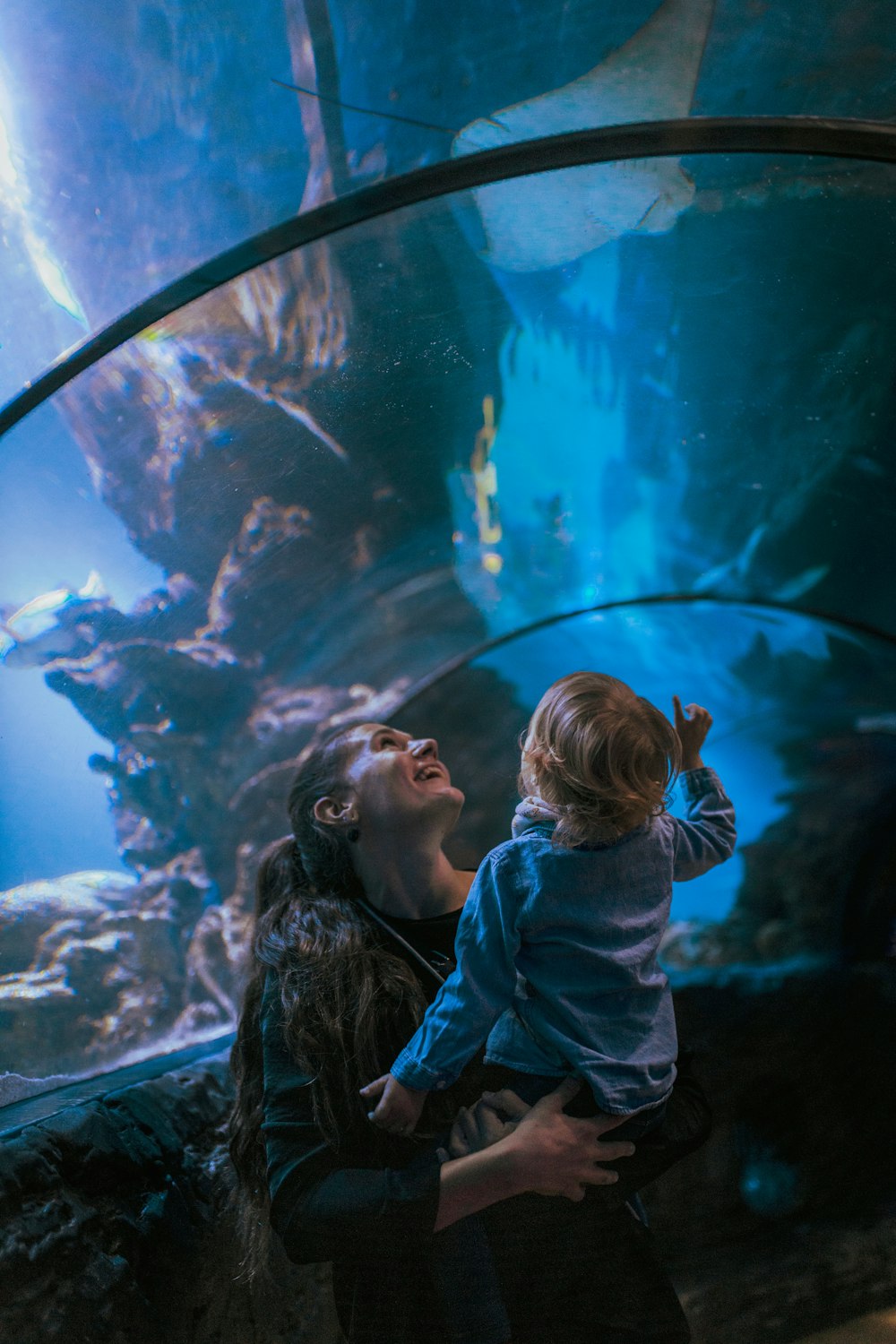 uma pessoa e uma criança olhando para um grande tanque de peixes
