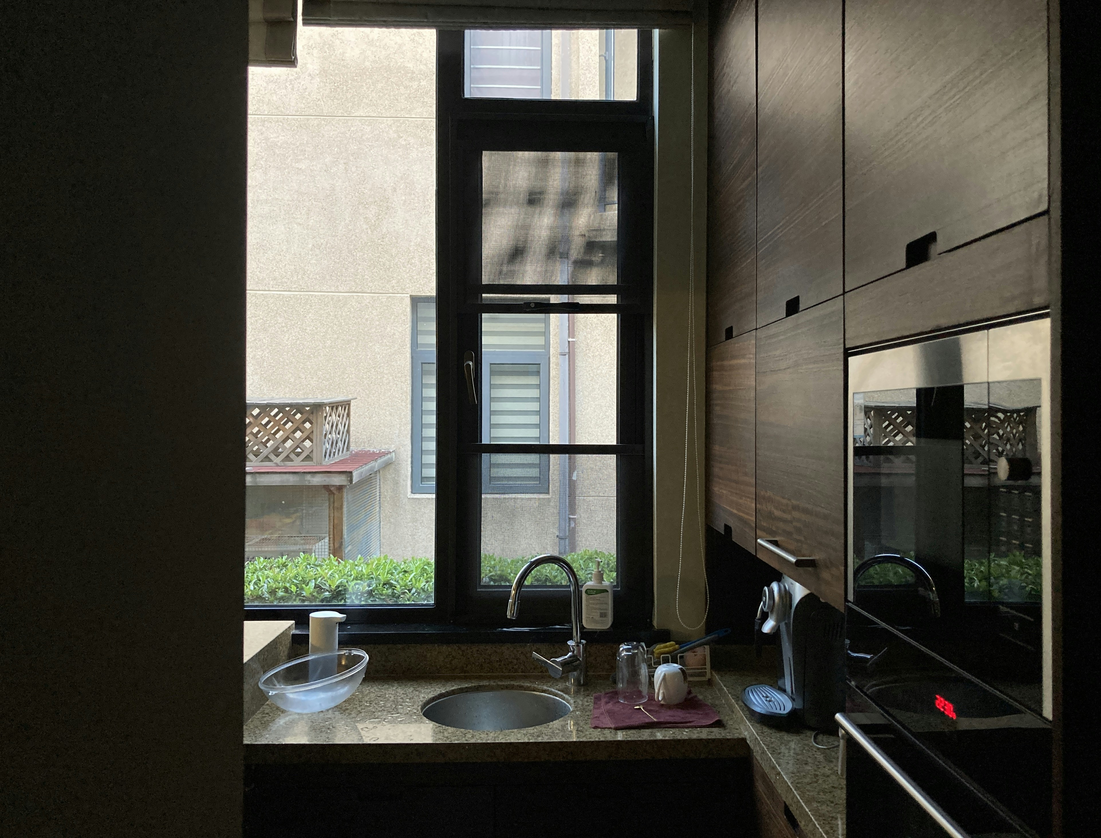 A sleek modern kitchen with dark cabinetry and a large window overlooking a busy city street - luxury apartments with views
