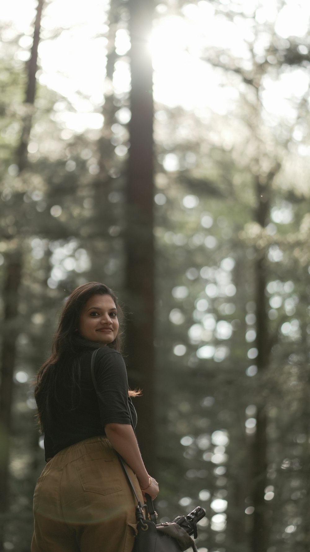 a woman with a purse standing in front of trees