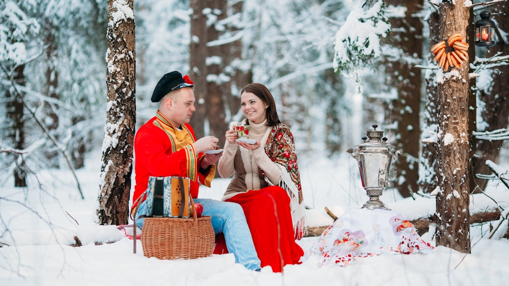 a man and woman sitting in the snow