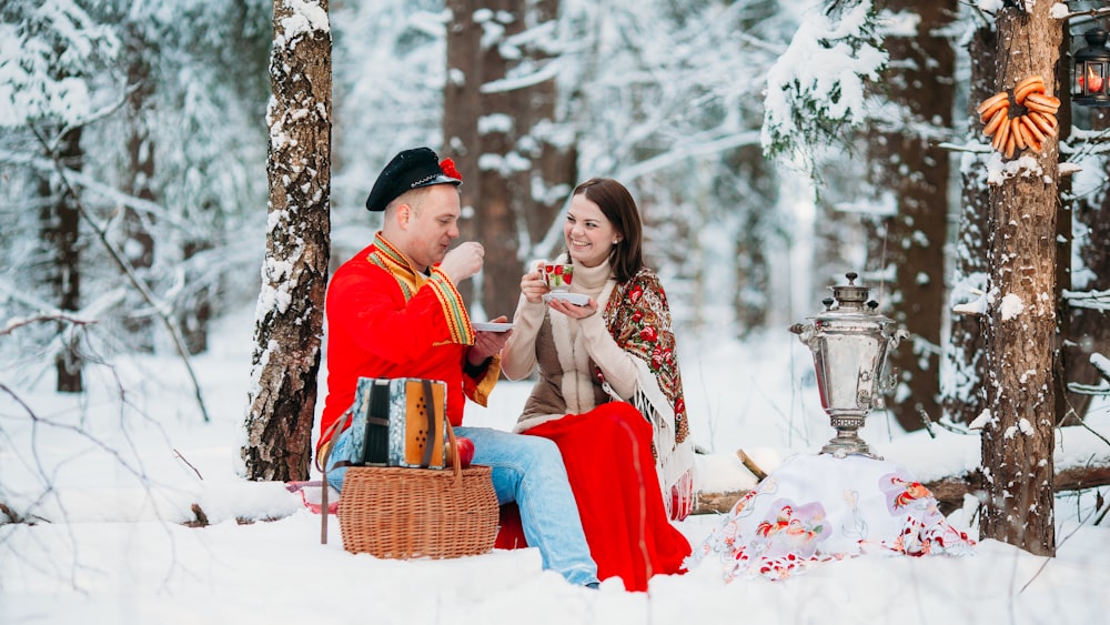 a man and woman sitting in the snow