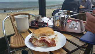 Happy customers enjoying bacon sandwiches at a cozy Phnom Penh café, sunlight streaming through the window.
