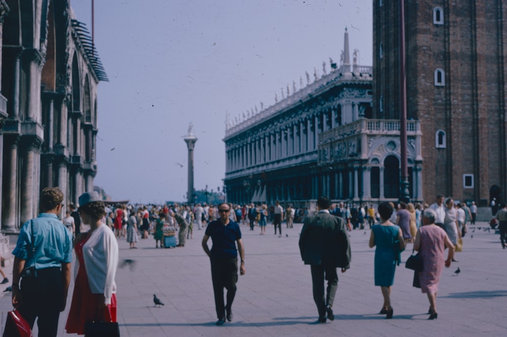 a group of people walking on a street between buildings